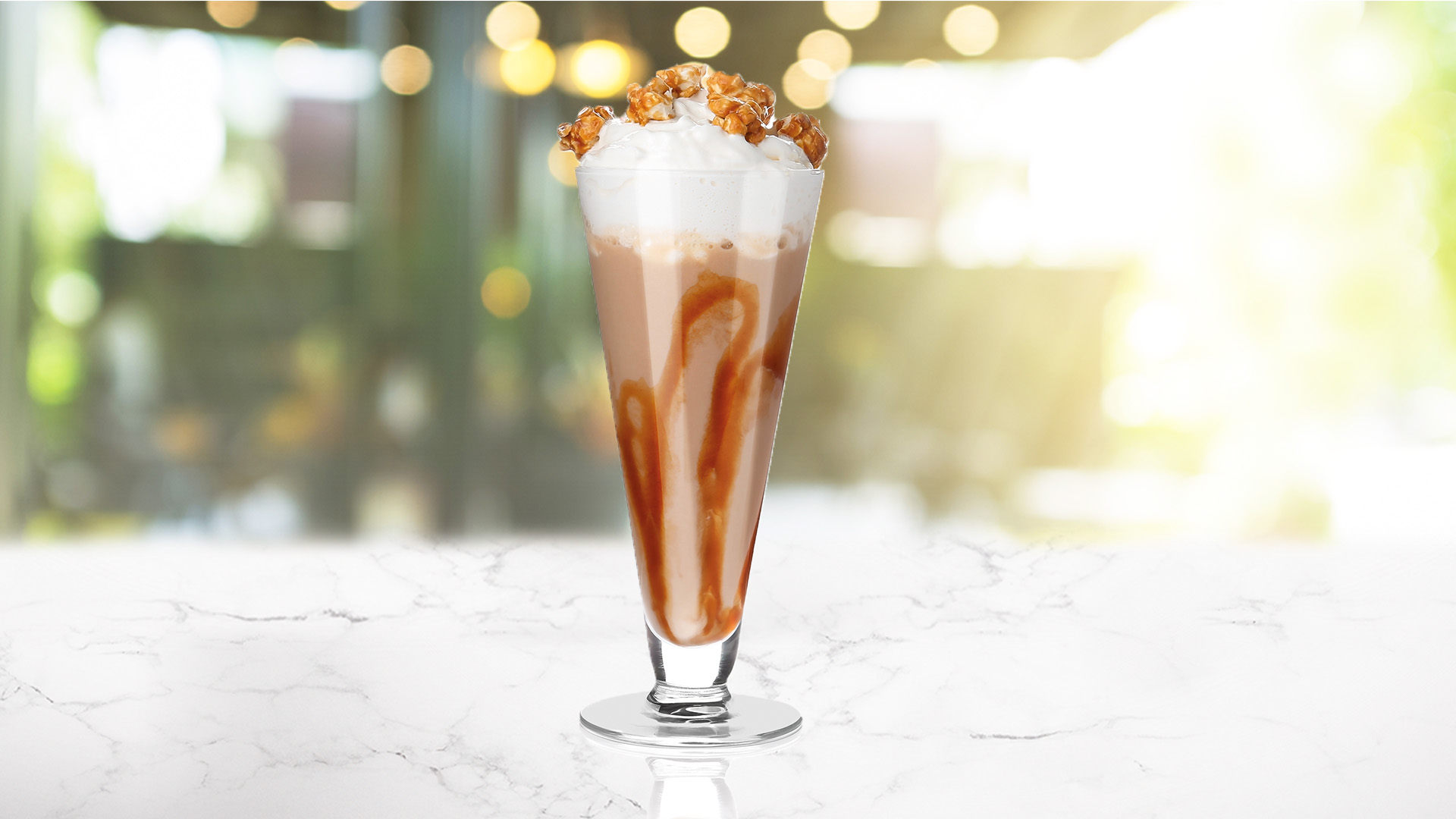 A glass of Iced Popcorn Boozy Frappe on a transparent background
