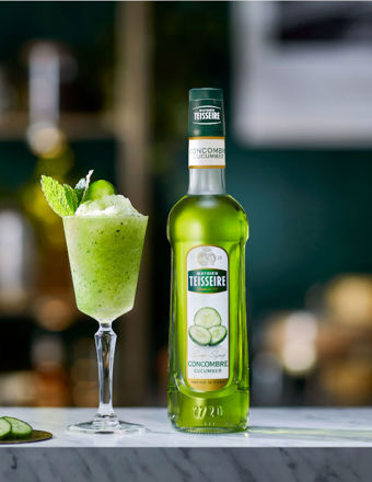 Bottle of Mathieu Teisseire cucumber syrup with a cocktail and garnish