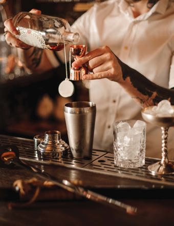 pouring a tot into a cocktail