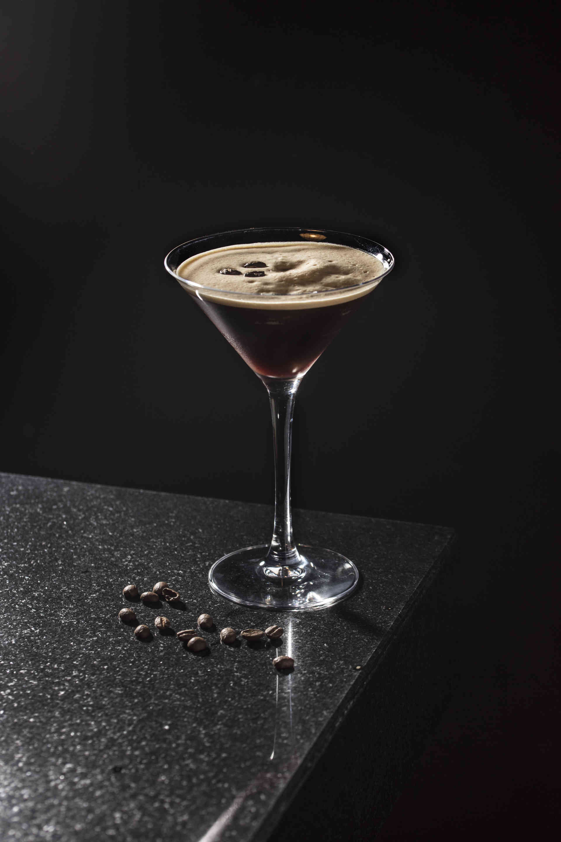 martini glass of Tiramisu Creamy Martini on the edge of a stone surface with loose coffee beans