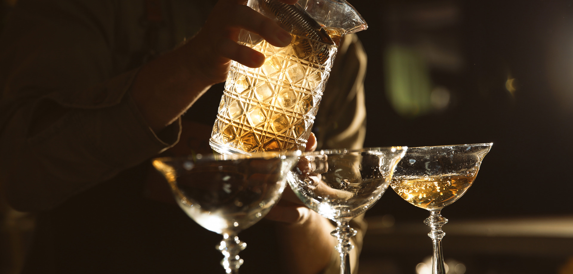 A bartender pouring drinks into a glass