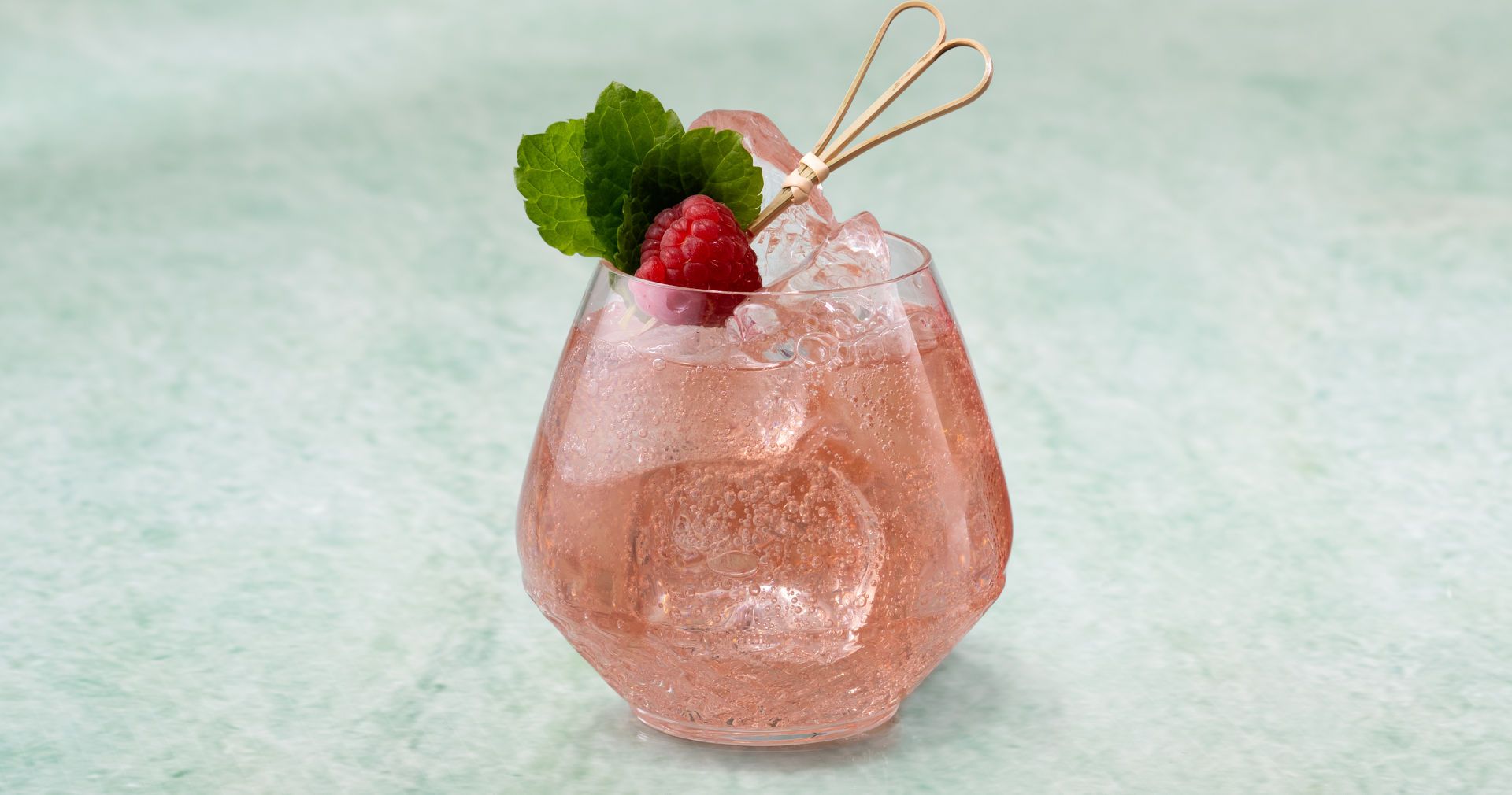 Glass of Raspberry Mint Cooler on a green stone surface