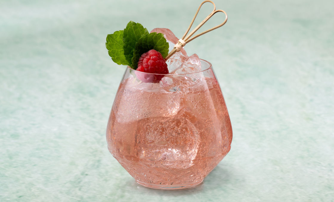 Glass of Raspberry Mint Cooler on a green stone surface