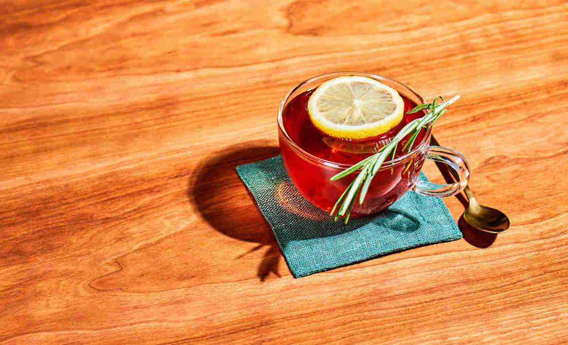 A top down shot of a glass of Rosemary Lemonade Iced tea on a small mat