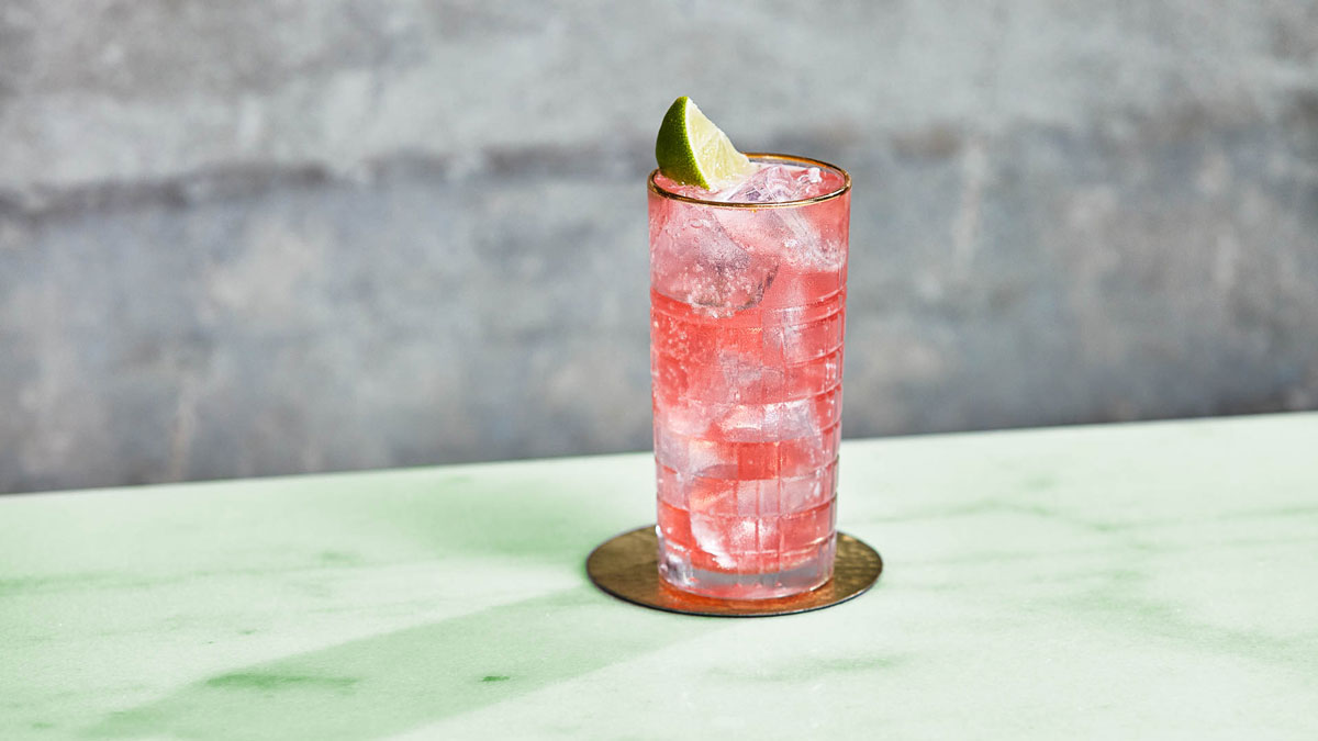 A glass of Cranberry and Lime Lemonade on a table outdoors