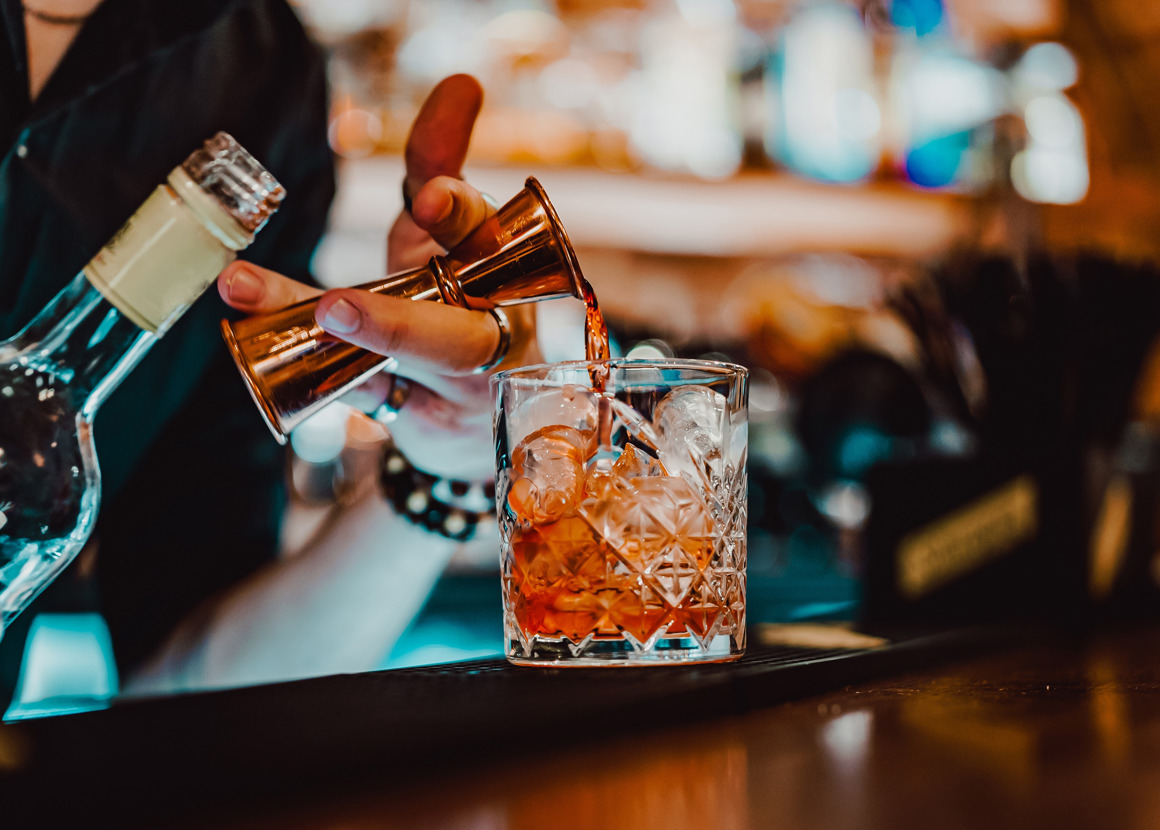 A bartender pouring a drink into a glass