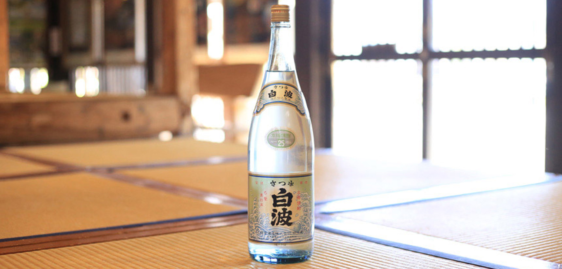 In the middle of a large table there is a bottle of shochu with labels written in japanese