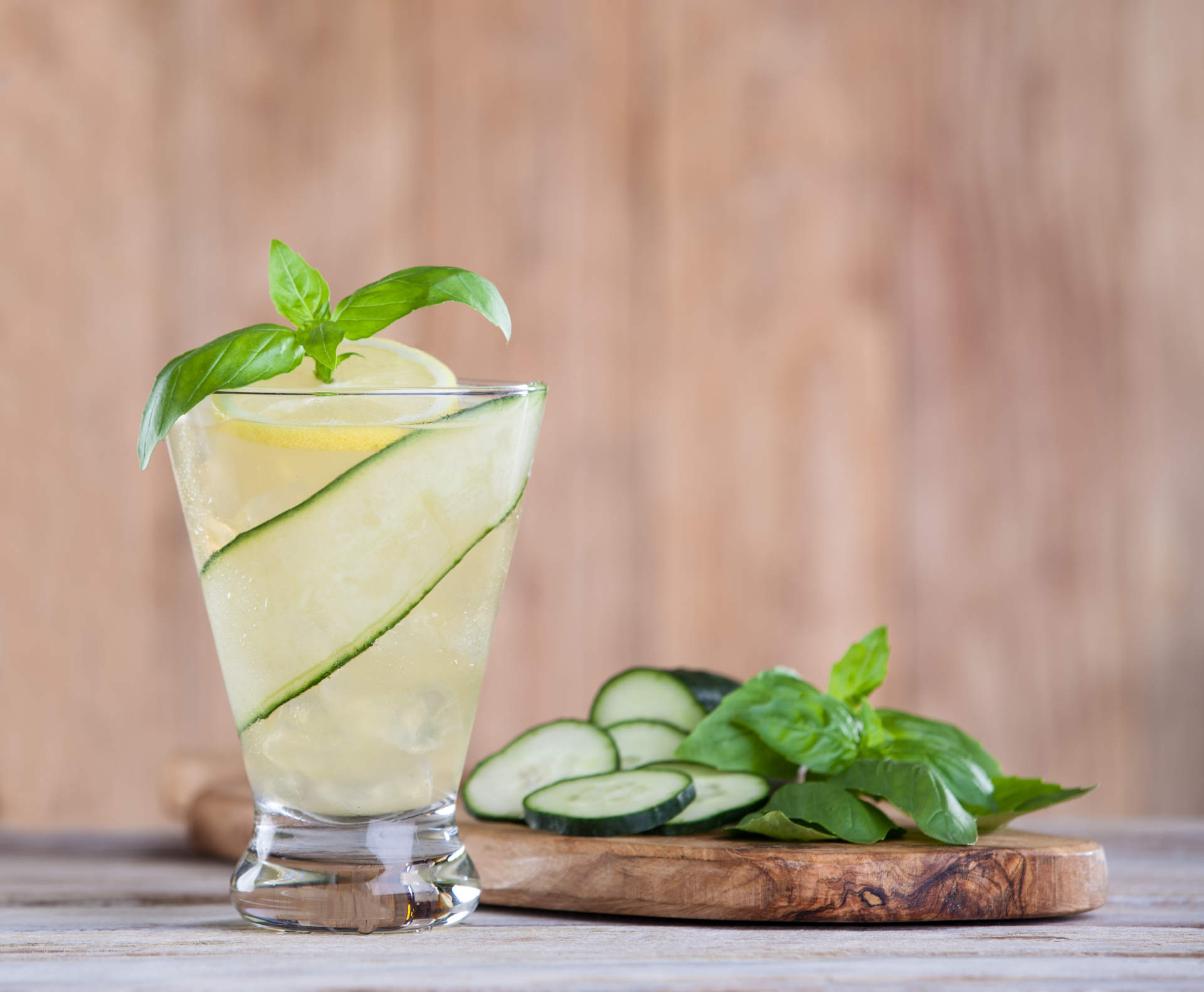 Basil Lemon Iced Tea with cucumber slides on a wooden slab