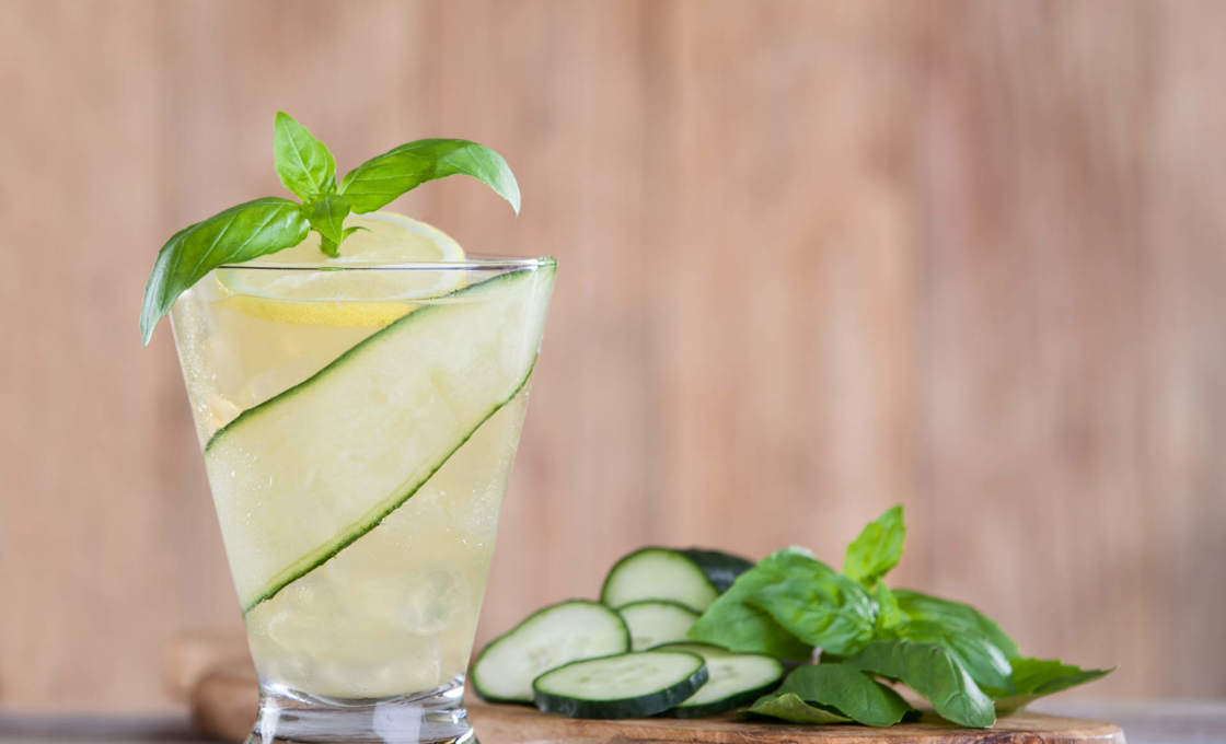 Basil Lemon Iced Tea with cucumber slides on a wooden slab