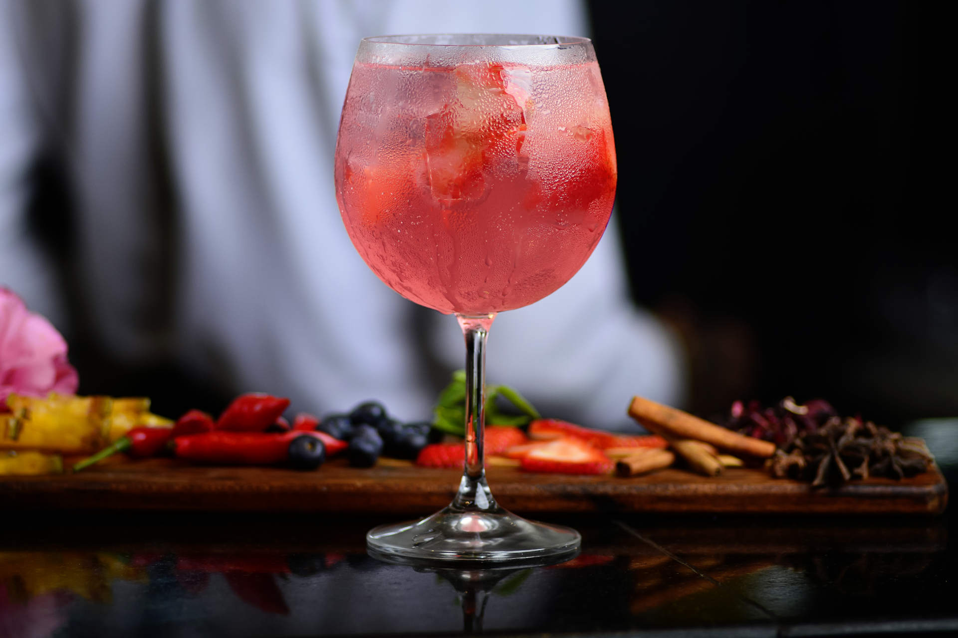 Fruity Vino in a glass beside spices on a dark bar
