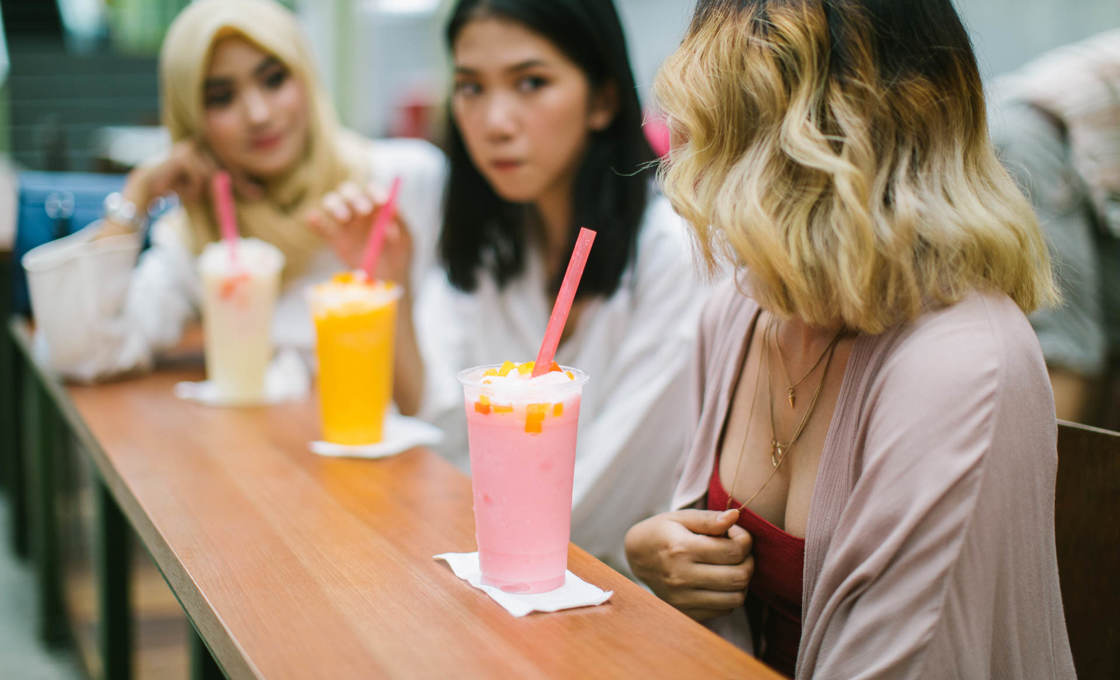 Multi-ethnic group of women sitting in the cafe and drinking milkshakes