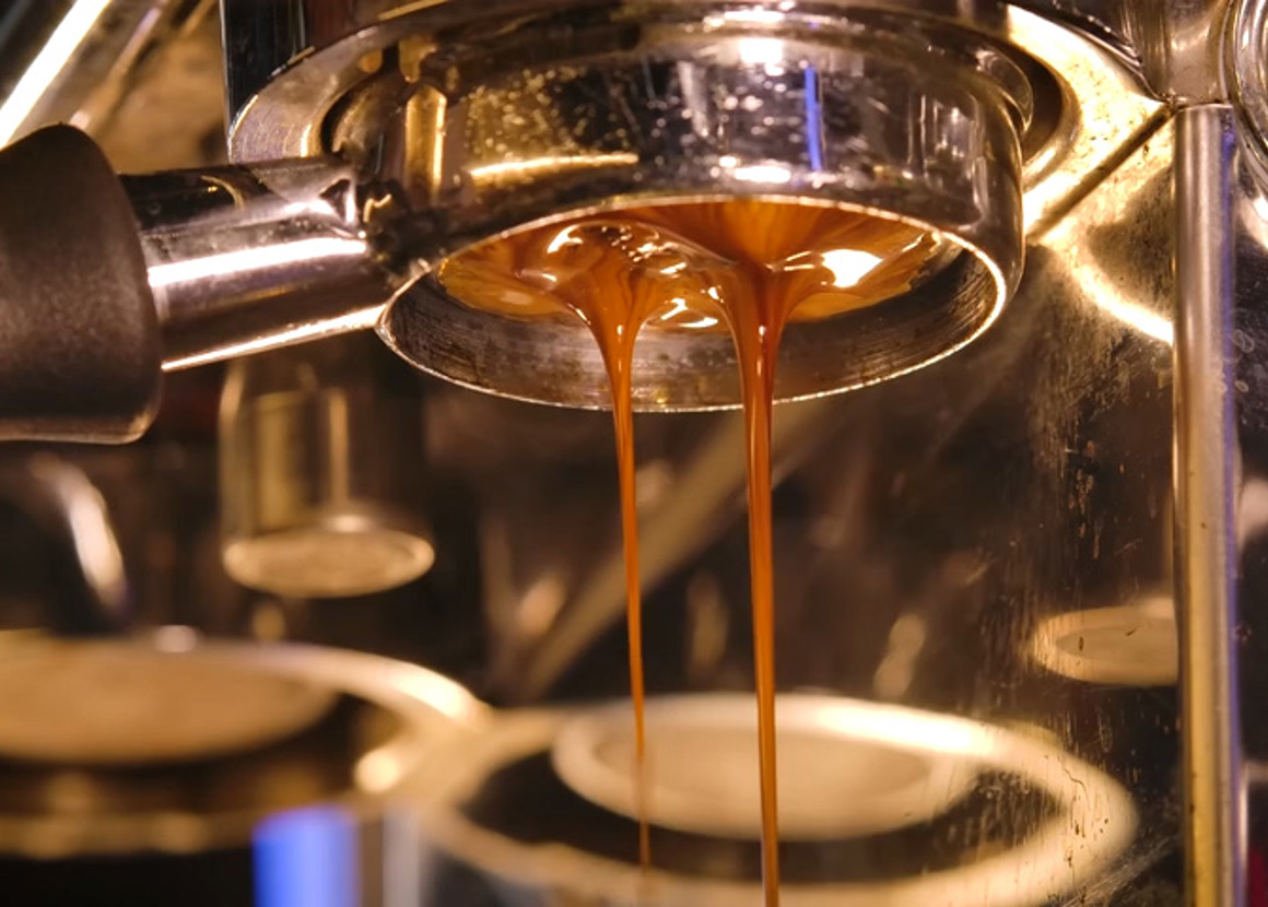 Close in, we can see coffee being poured through a coffee machine.