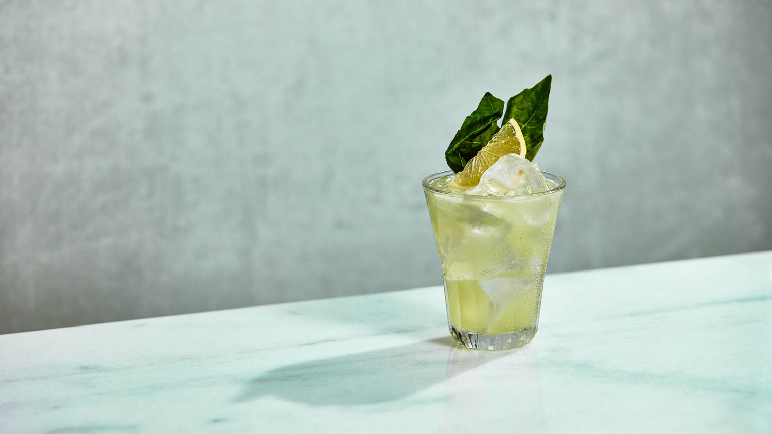 A glass of Basil Smash on a textured surface