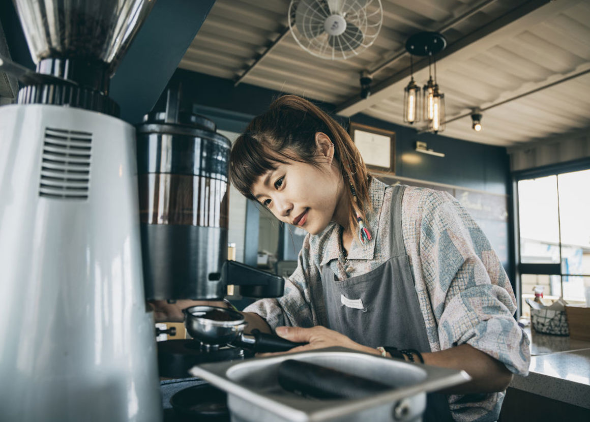 A female barista making coffee