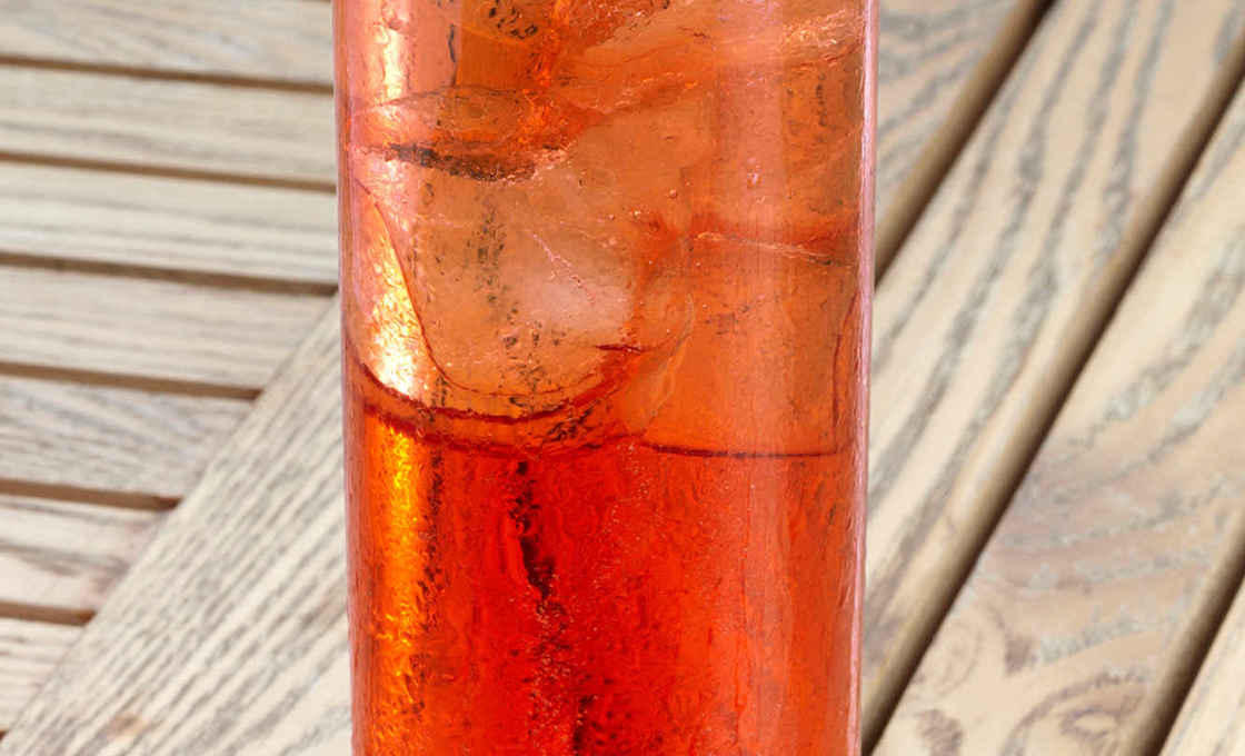 Tall glass of Cherry & Peach Sparkler on a wooden table