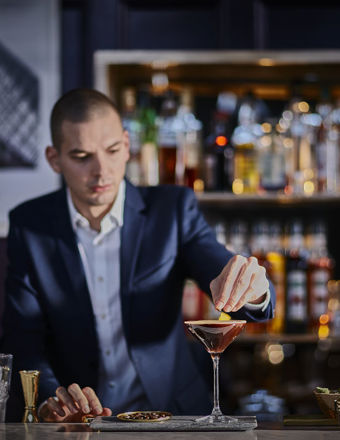 Man in a suit garnishing a cocktail