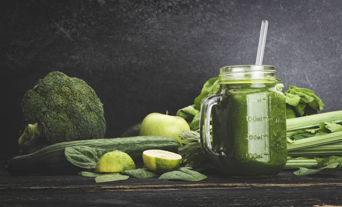 Spicy veggie smoothie with an assortment of green vegetables on a rustic table