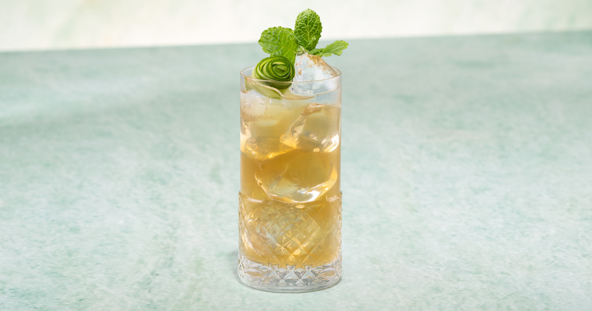 Glass of Emerald Green Iced Tea on a green stone surface