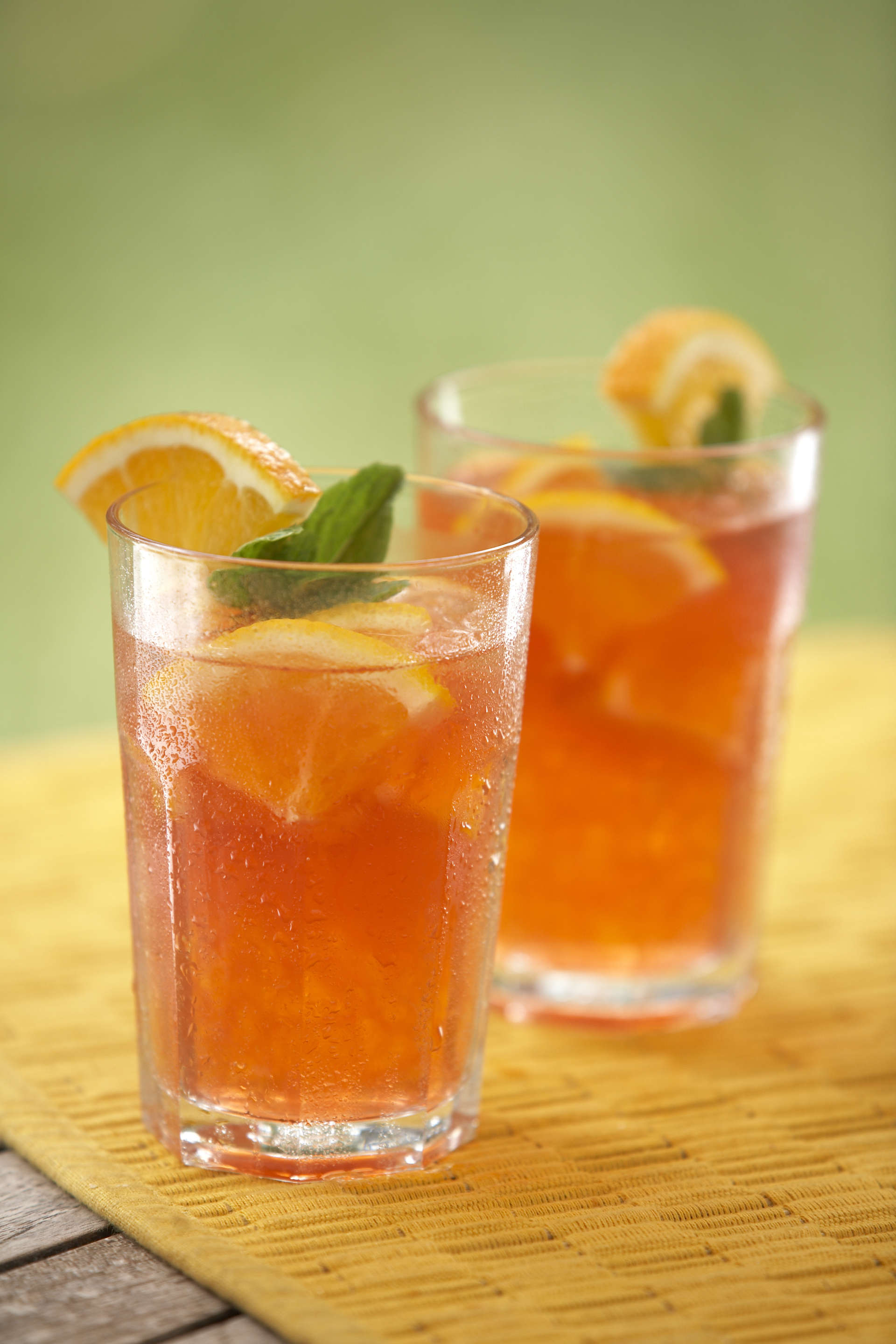 Two glasses of melon tea with a blurred out green background